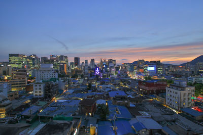 High angle view of illuminated city buildings against sky during sunset