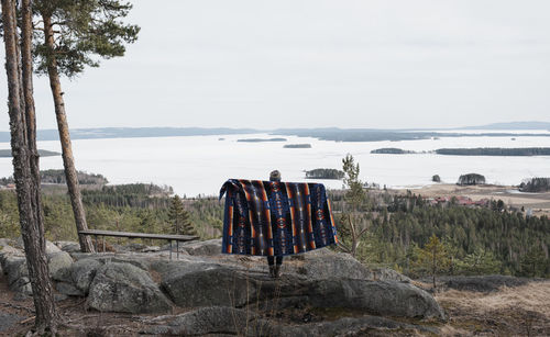 Rear view of men sitting on rock against sky