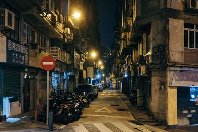 Illuminated street amidst buildings at night