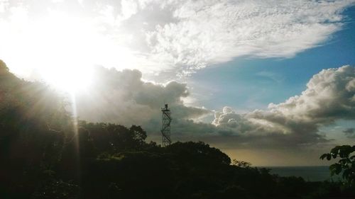 Low angle view of trees against cloudy sky