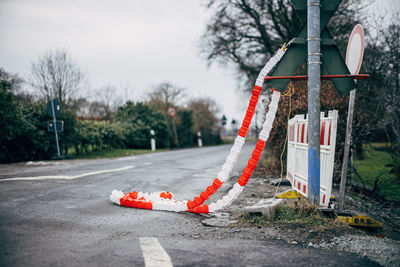 Red flags on road by trees against sky