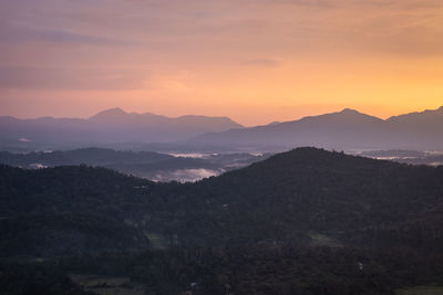 Mountains range misty shadow with dramatic colorful sunset sky at dusk from flat angle