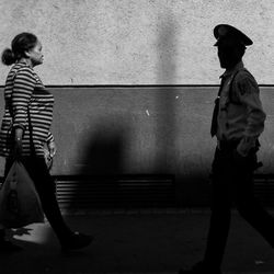 Side view of man and woman walking on wall