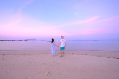 Woman standing on beach against sky during sunset