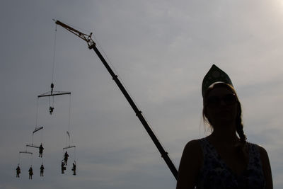 Low angle view of silhouette woman holding umbrella against sky