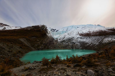 Scenic view of lake by snowcapped mountains against sky