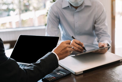 Midsection of man using laptop on table