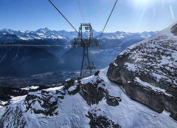 Overhead cable car over snowcapped mountains against sky