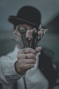 Woman holding wrenches and flowers