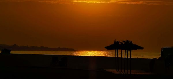 Silhouette people on beach against sky during sunset