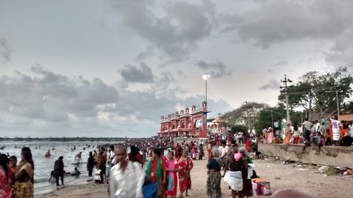 People at amusement park against cloudy sky