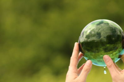 Close-up of hand holding crystal ball against blurred background