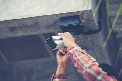 Low angle view of maintenance engineer installing security camera on wall