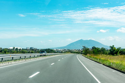 Empty road along landscape and mountains against sky