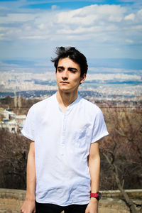 Portrait of young man standing against sky