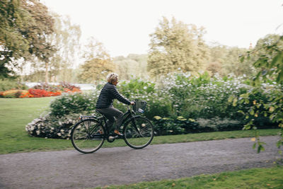 Full length of senior woman riding bicycle in park