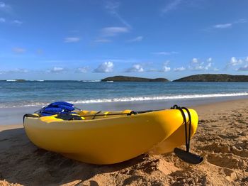 Boats moored on beach against blue sky