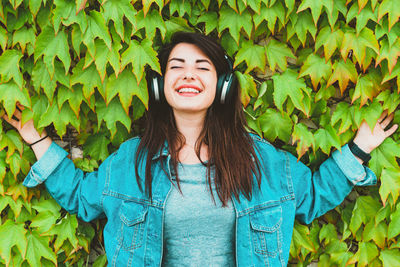 Portrait of smiling young woman standing by leaves