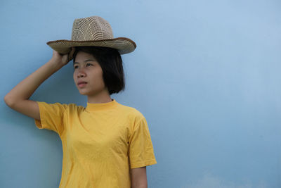 Portrait of woman wearing hat against wall