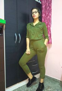 Portrait of a young woman standing against wall