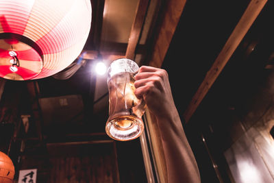 Cropped hand holding beer glass by lantern
