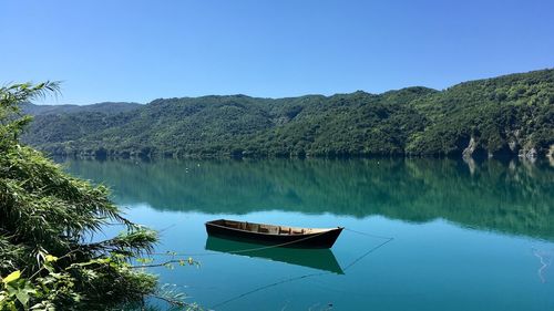 Boat in lake against clear blue sky