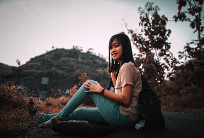 Side view of a young woman sitting outdoors