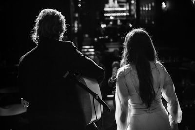 Rear view of people standing in city at night