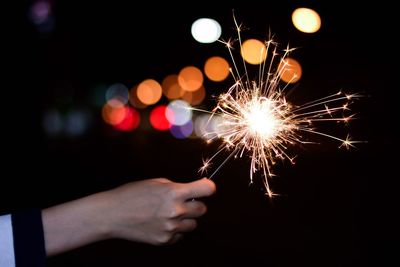 Cropped hand holding illuminated sparkler