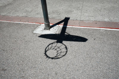 Shadow of basketball hoop on street during sunny day