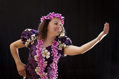 Close-up of woman wearing flowers while dancing against wall