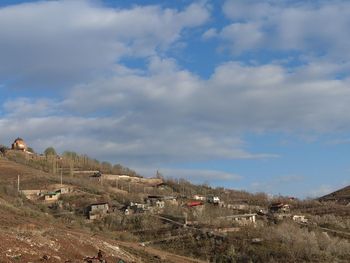 Houses on field by buildings against sky