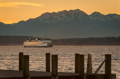 Ferry boat in puget sound against mountain during sunset