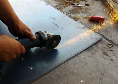 Close-up of man cutting metal with grinder at workshop