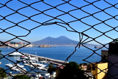 Close-up of chainlink fence in city against clear sky