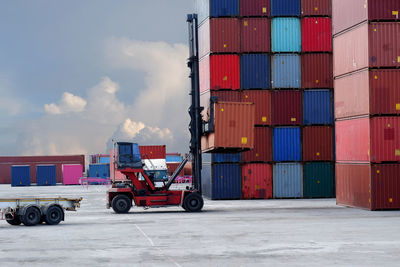 Stack of truck on pier at harbor against sky