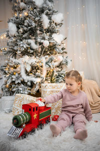 Portrait of cute girl playing with christmas tree at home