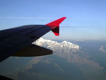 Close-up of airplane flying over mountains against blue sky