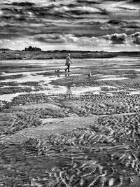 Man walking on beach against sky