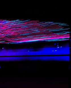 Multi colored light trails on pink lights at night