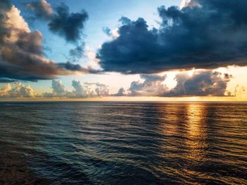 Scenic view of sea against dramatic sky during sunset