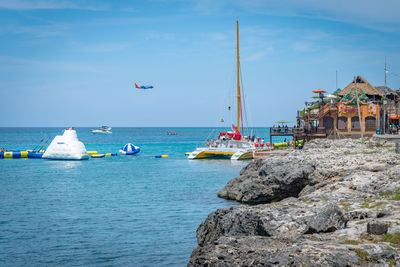 Sailboats on sea shore against sky