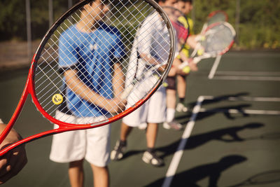 Players standing in row playing tennis at court