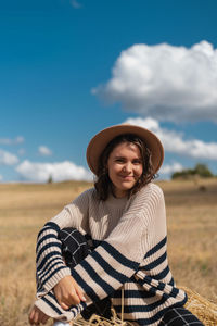 Portrait of smiling young woman on field against sky