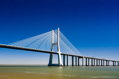 Low angle view of suspension bridge against blue sky