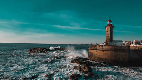 Lighthouse by sea against sky