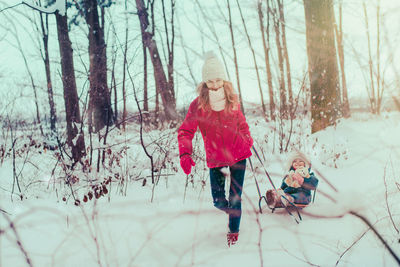 Mother and daughter wearing warm clothing playing in snow during winter