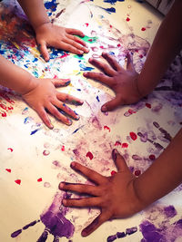 Cropped hands of children hand painting on paper