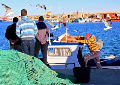 People sitting on boat in sea against sky