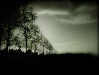 Silhouette trees on landscape against cloudy sky